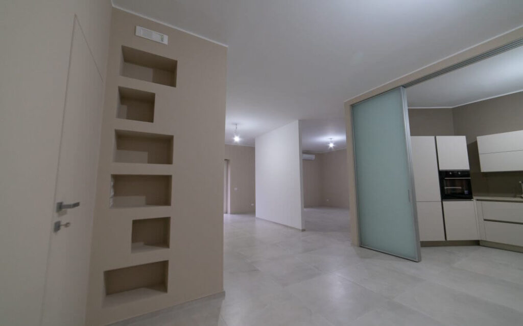 Interno moderno, appartamento vuoto, nicchie a muro, porta scorrevole.